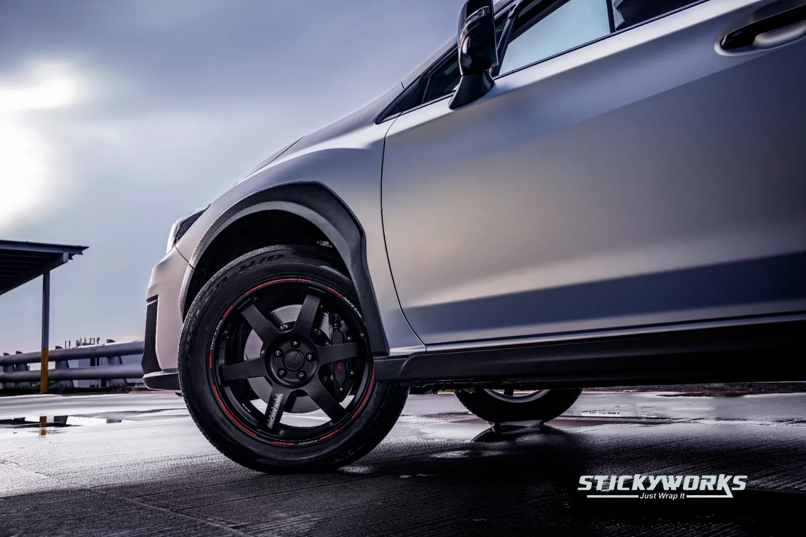 Close-up of a silver vehicle wheel and lower body finished with a car wrap