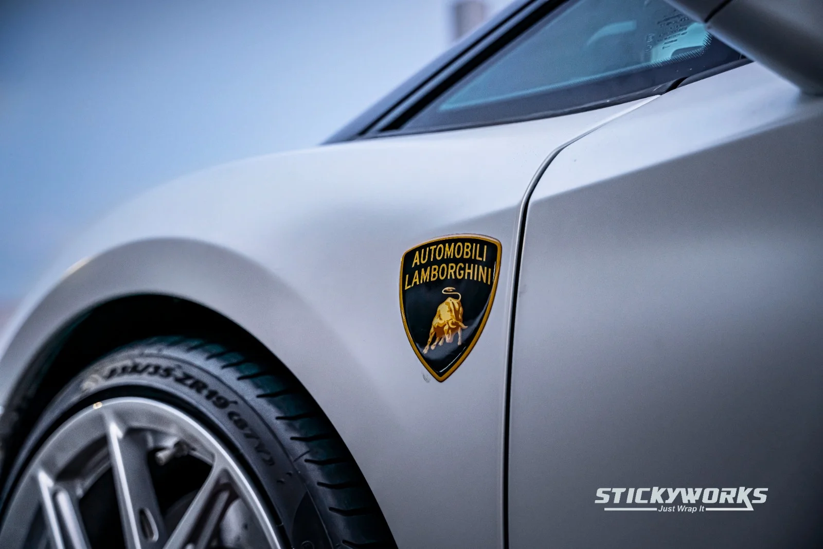 StickyWorks Lamborghini fender and badge detail in matte white wrap highlighting precision and seamless edges