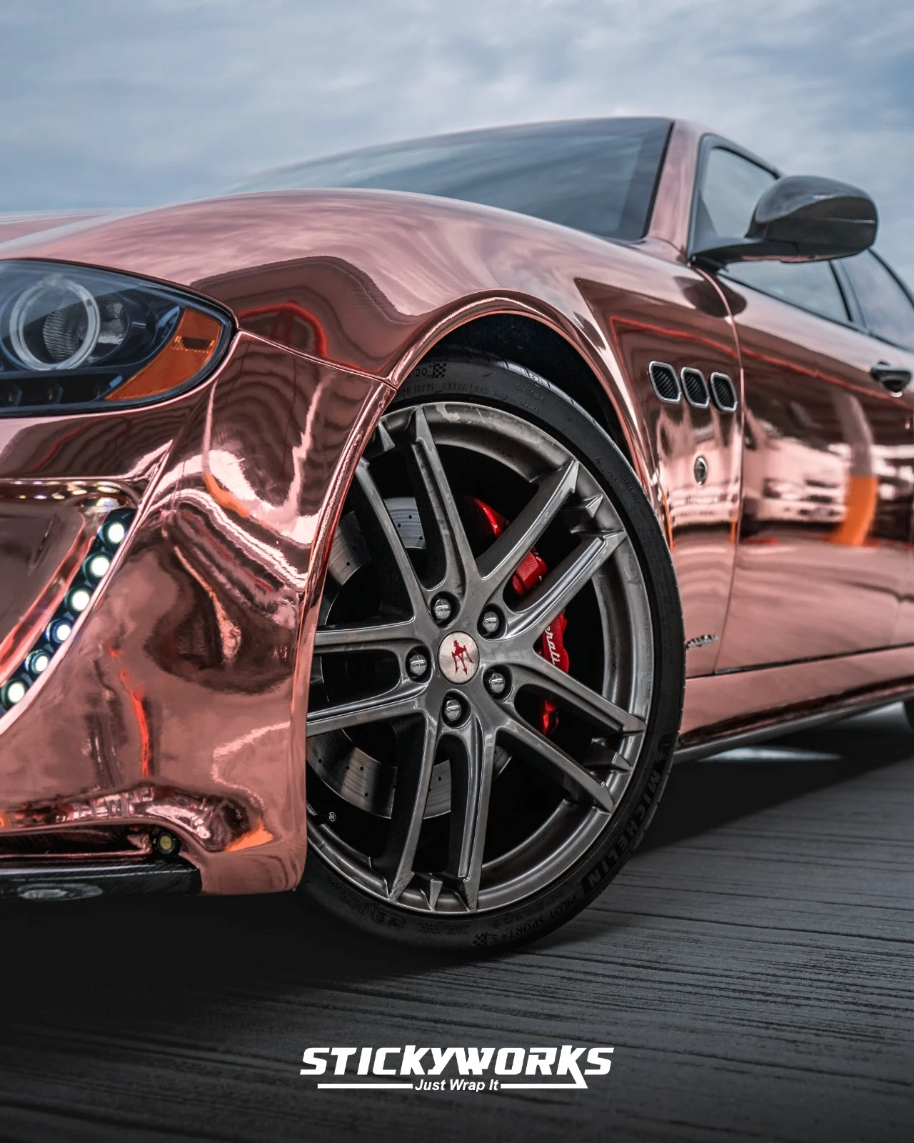 StickyWorks Maserati wheel close-up with rose gold chrome wrap reflecting surroundings and highlighting premium finish