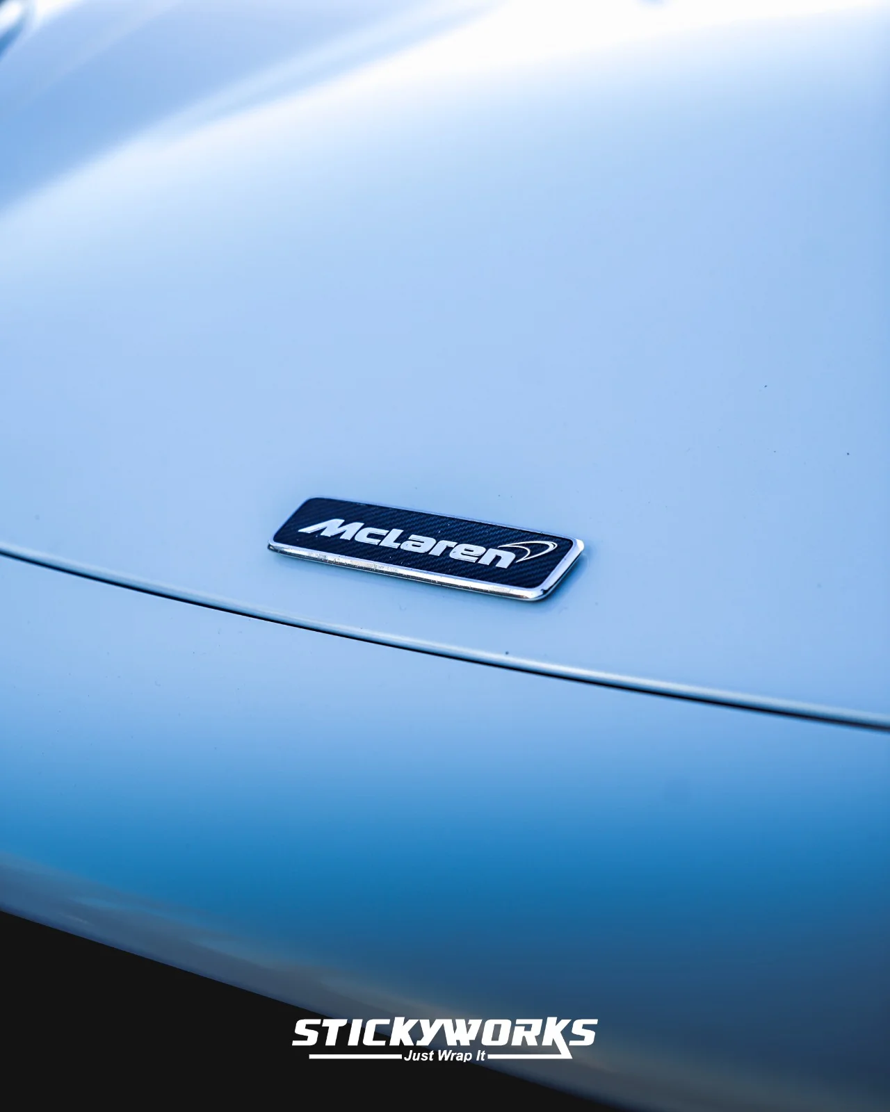StickyWorks McLaren badge close-up on gloss white wrap highlighting smooth surface and refined detailing