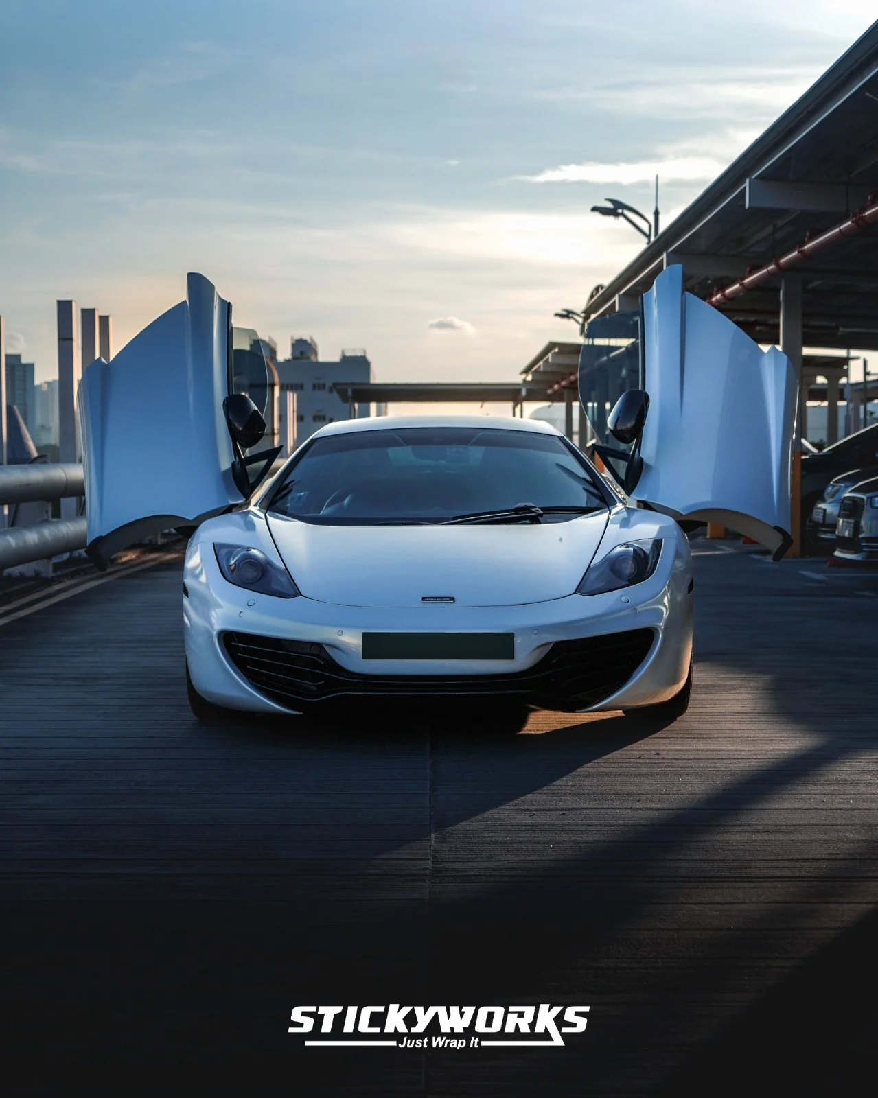 StickyWorks McLaren front view with doors open in gloss white wrap showcasing premium finish and symmetry