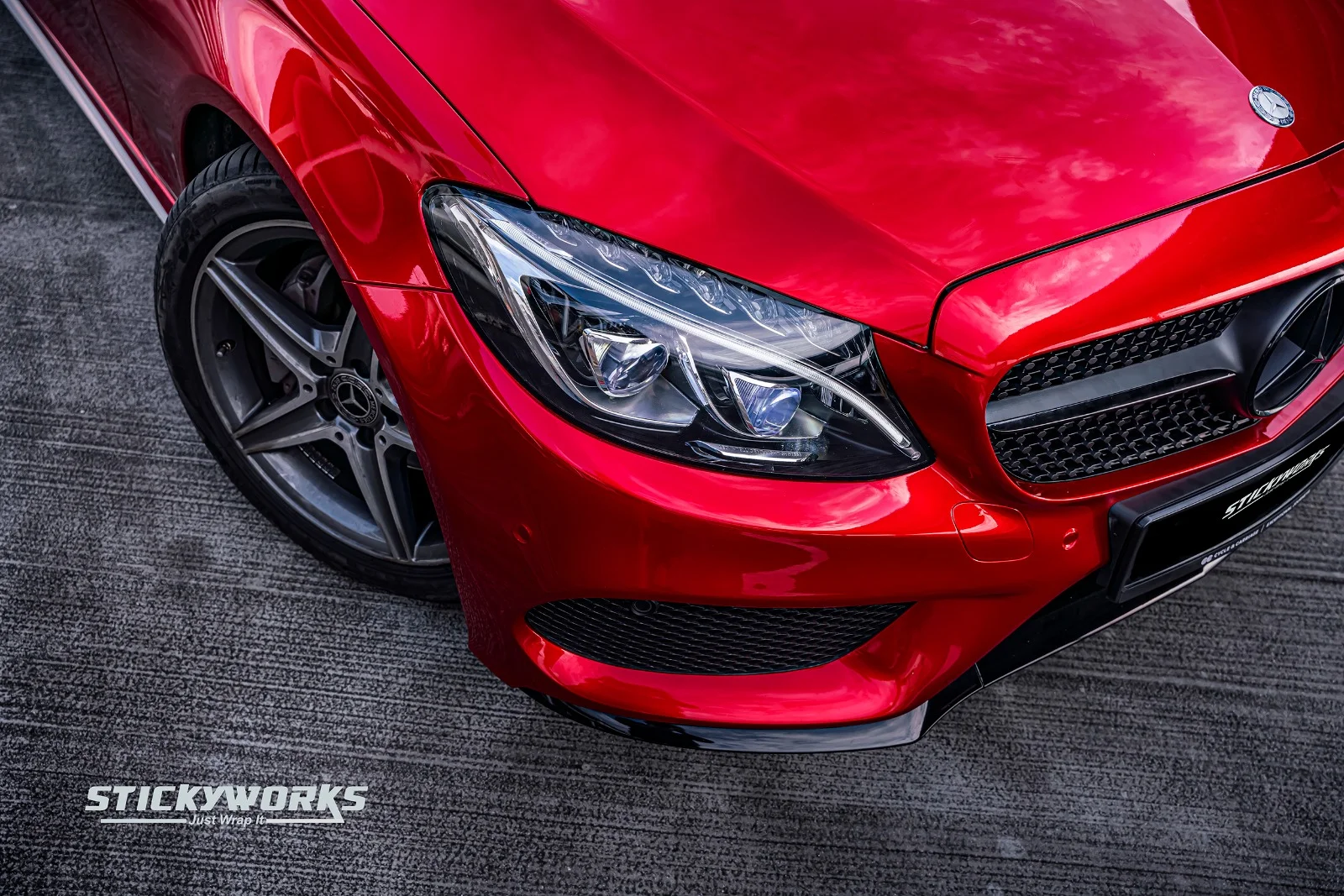 StickyWorks Mercedes headlight close-up with gloss red wrap highlighting precision and clean detailing