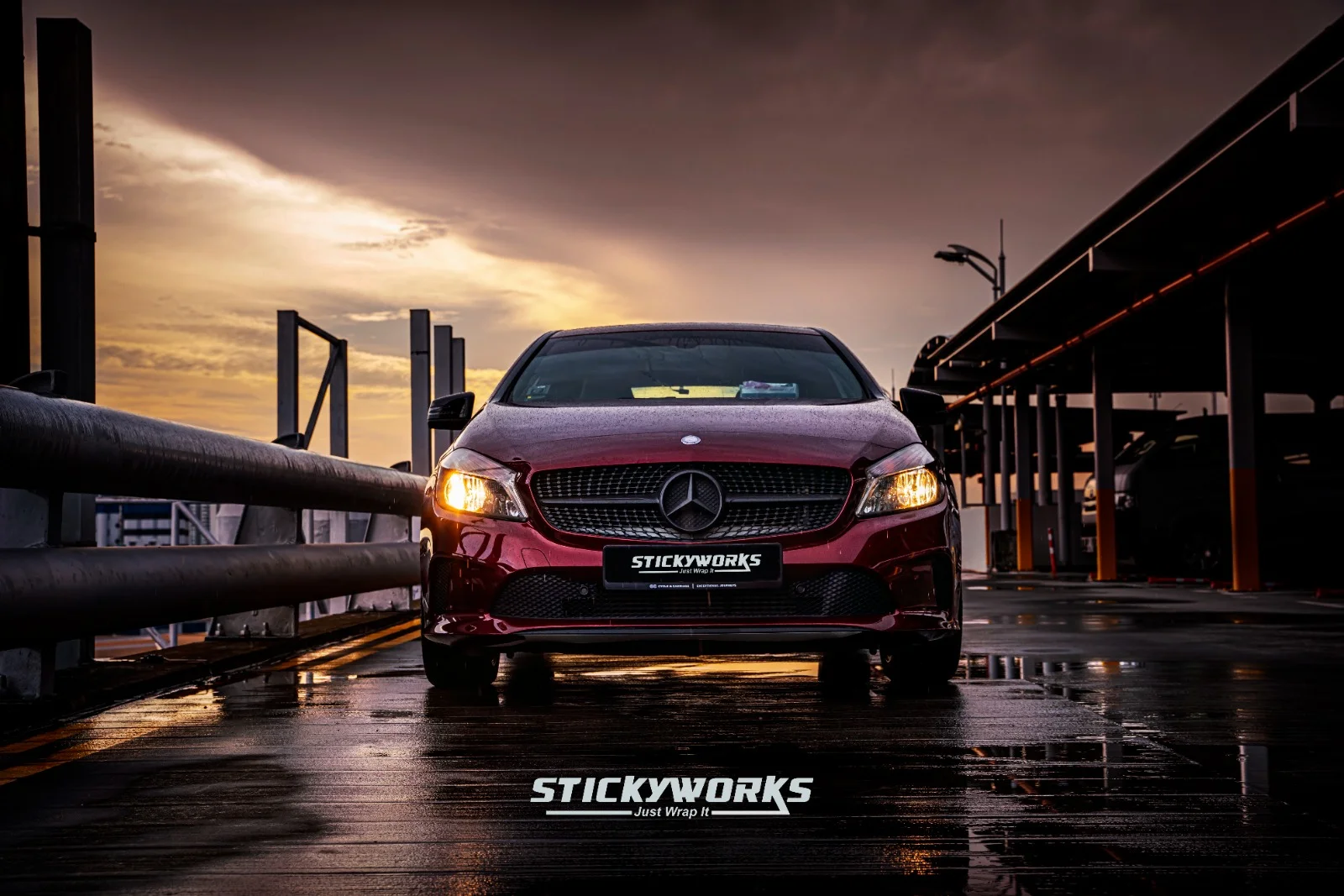 StickyWorks Mercedes front shot in gloss red wrap under sunset lighting emphasizing premium finish and styling