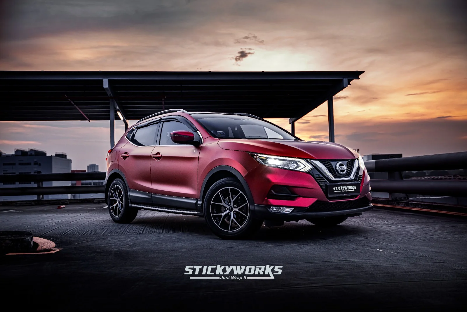 StickyWorks Nissan Qashqai red satin wrap front angle shot during sunset highlighting smooth vinyl finish
