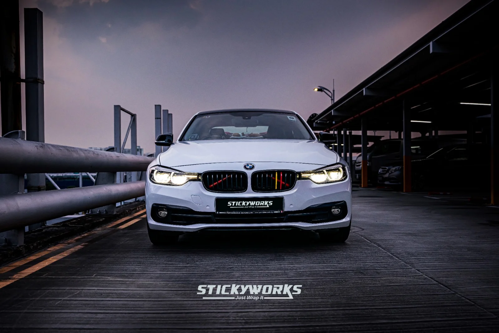 Front view of white BMW 3 Series with custom vinyl wrap and enhanced lighting detail