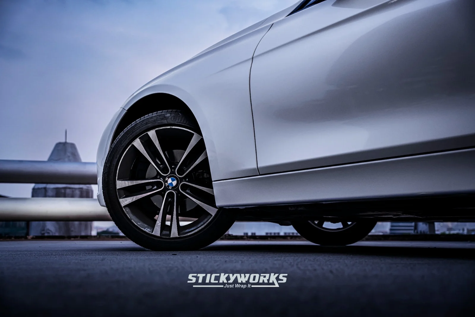 Close-up of BMW wheel and side panel highlighting smooth vinyl wrap finish and detailing