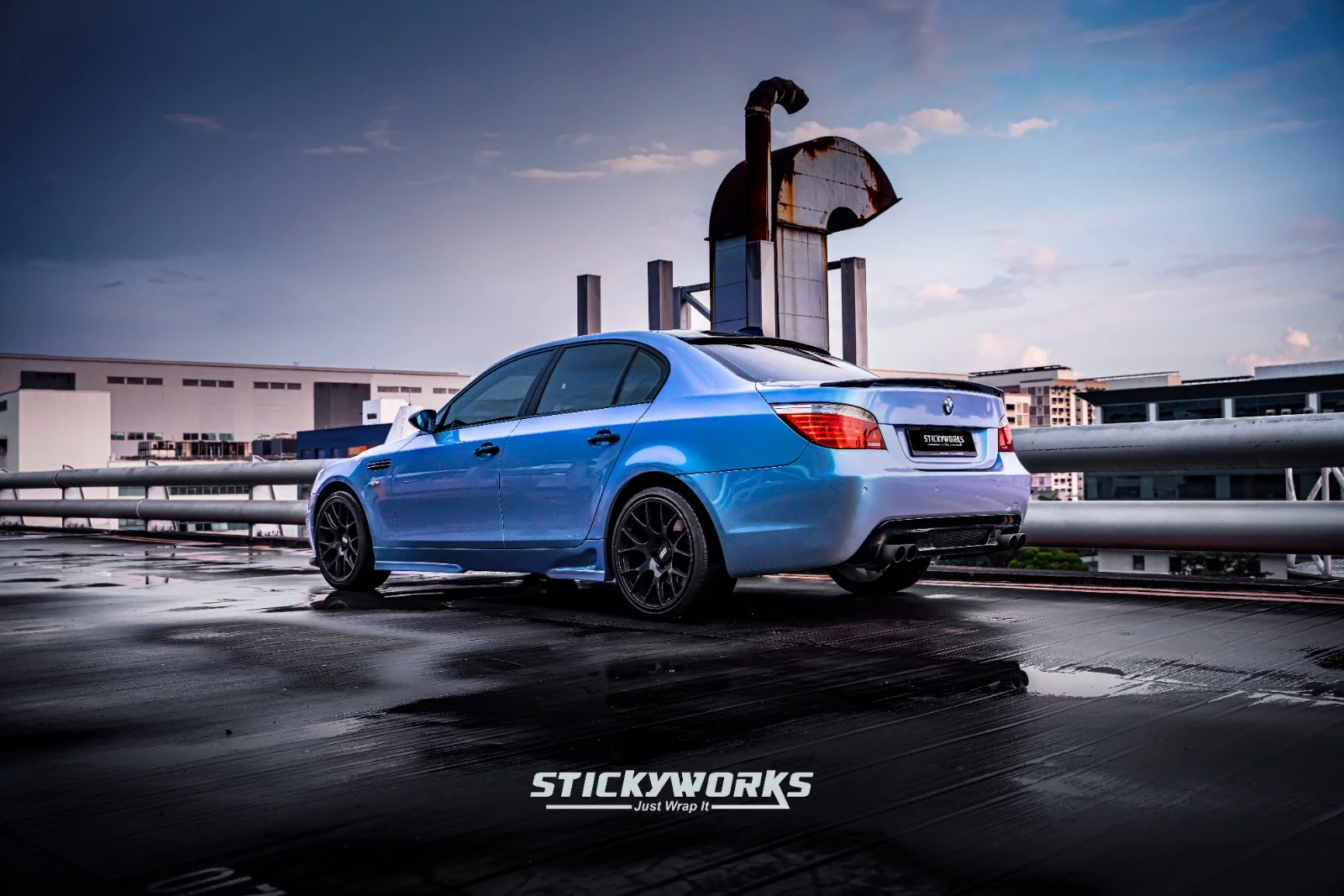 Blue BMW M5 front angle with custom wrap reflecting sunset lighting and glossy finish