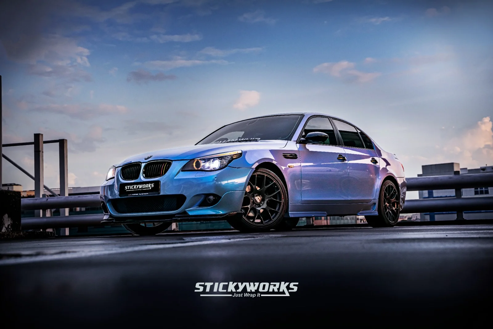 Front view of blue BMW M5 at night with illuminated headlights and custom wrap finish