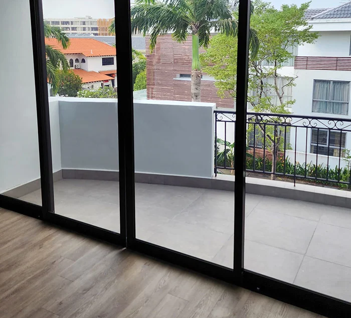 Sliding balcony windows with solar film reducing heat and glare in a Singapore home overlooking greenery and nearby houses